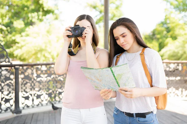 若い女性読書マップ一方 友人は一緒に週末旅行中にいくつかの写真を撮る — ストック写真