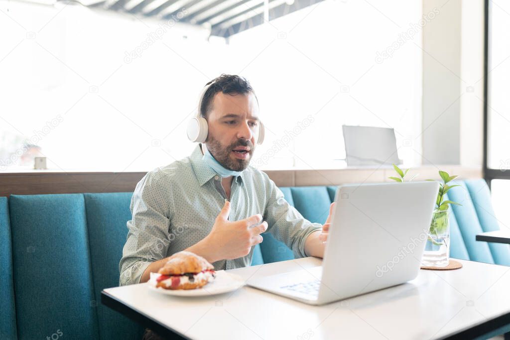 Caucasian mid adult man video calling through laptop in restaurant