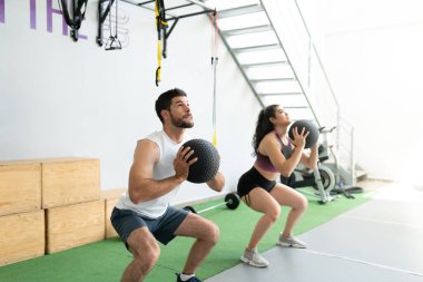 Atletik Latin erkek ve kadın spor salonunda duvar toplarıyla egzersiz yapıyor.