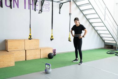 Kettlebell 'le sağlık kulübünde antrenman yaptıktan sonra ara veren genç bir kadın.