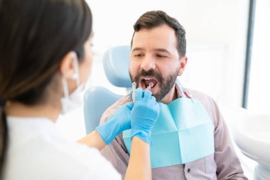 Görünmez diş teli olan kadın ortodontist yetişkin adamı muayene ediyor.