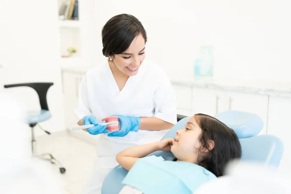 Pewna Siebie Biała Dentystka Showign Małą Dziewczynkę Jak Prawidłowo Myć — Zdjęcie stockowe