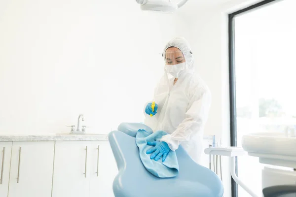 Dentystka Kombinezonie Ochronnym Czyszcząca Klinikę Stomatologiczną Szmatą Sprayem Podczas Kryzysu — Zdjęcie stockowe