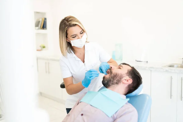 Dentystka Masce Twarzy Podczas Sprawdzania Zębów Pacjenta Klinice Ortodontycznej — Zdjęcie stockowe
