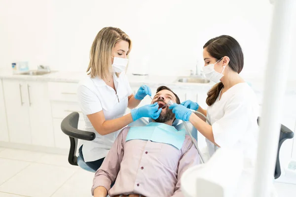 Dentistas Mulheres Examinando Homem Adulto Médio Caucasiano Durante Tratamento Odontológico — Fotografia de Stock