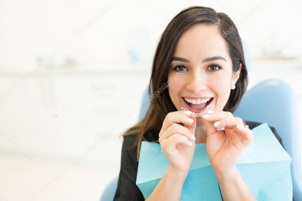 Happy mid adult woman with clear orthodontic retainer in dental clinic