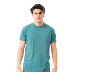 Yakışıklı genç adam beyaz arka planda dururken kaşlarını çatıyor.