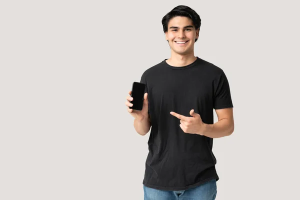 Boa Aparência Sorridente Jovem Apontando Dedo Para Smartphone Enquanto Estava — Fotografia de Stock