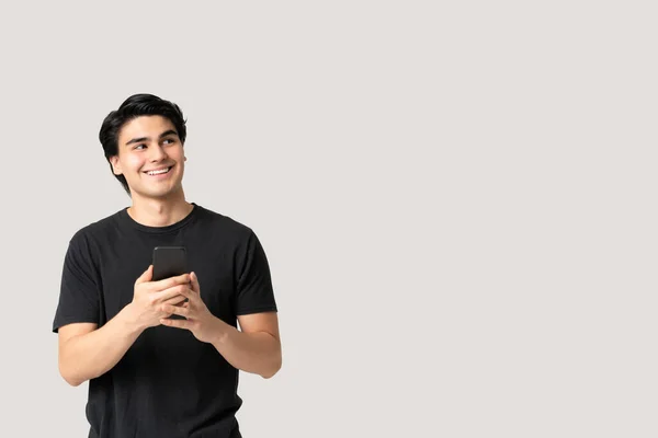 Sorrindo Pensativo Latino Jovem Olhando Para Espaço Branco Usar Smartphone — Fotografia de Stock