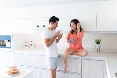 Mutfakta kahve içerken konuşan mutlu genç çift.