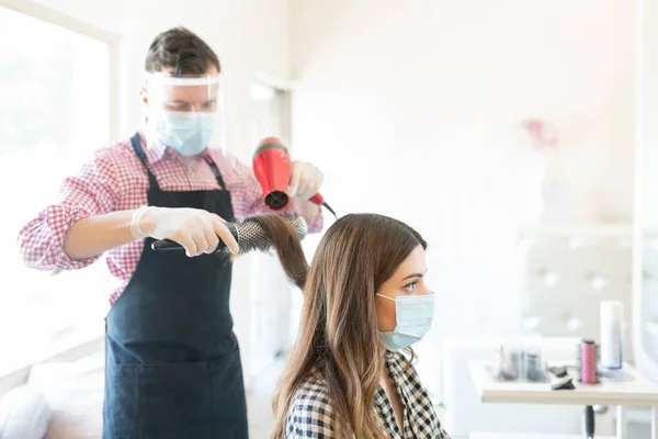 在珊瑚爆发期间 美容院的男性理发师在女性顾客身上使用吹风机 — 图库照片