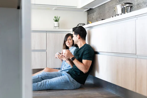 Sorrindo Jovem Casal Beber Café Enquanto Sentado Chão Cozinha — Fotografia de Stock