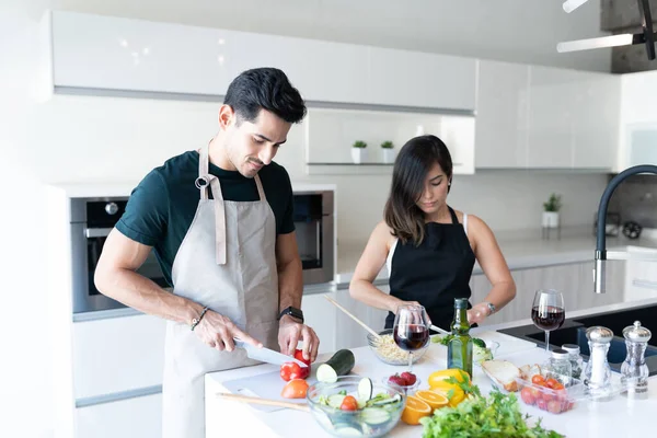 西班牙裔年轻夫妇在家里做意大利面的同时切蔬菜 — 图库照片