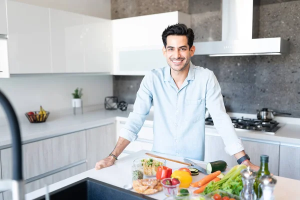 Lächelnder Gut Aussehender Junger Mann Mit Verschiedenen Gemüsesorten Auf Kücheninsel — Stockfoto