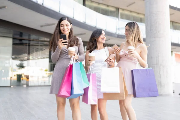 Szczęśliwe Piękne Kobiety Torbami Zakupy Pomocą Smartfonów Stojąc Zewnątrz Centrum — Zdjęcie stockowe