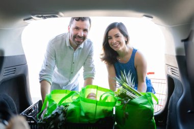 Bagajında alışveriş torbaları olan gülümseyen bir çiftin portresi.