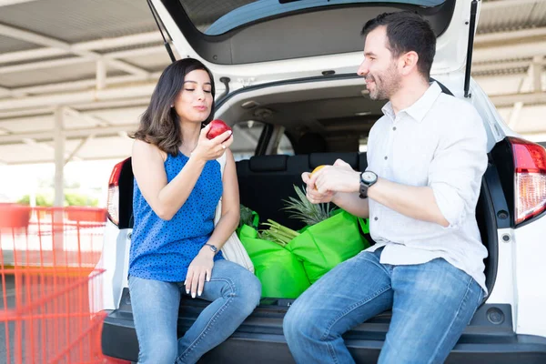 Sorridente Coppia Mangiare Frutta Mentre Seduto Borse Della Spesa Bagagliaio — Foto Stock