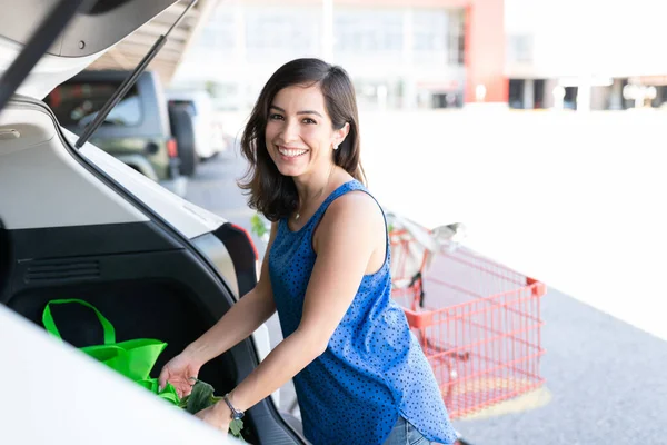 スーパーから買い物をした後 車のトランクに食料品袋をロードする美しい女性の笑顔 — ストック写真