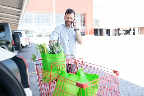 Sorrindo Homem Hispânico Falando Smartphone Enquanto Está Com Carrinho Compras — Fotografia de Stock