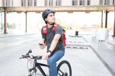 Sokakta bisiklet sürerken adres arayan İspanyol kurye.