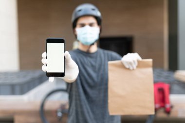COVID-19 sırasında paket teslim ederken akıllı telefon gösteren teslimatçı.