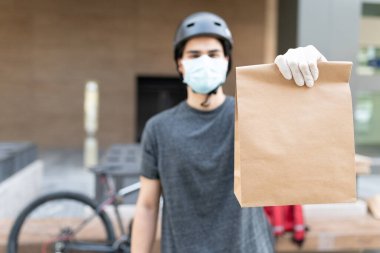 COVID-19 sırasında şehre paket teslim ederken yüz maskesi takan teslimatçı.