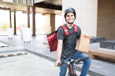 Bisikletin üzerinde oturan kendinden emin teslimatçı.