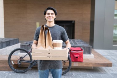 Yemek paketi taşıyan yakışıklı teslimatçının portresi.