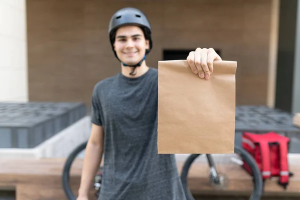 Sorrindo Jovem Entregador Mostrando Parcela Enquanto Estava Cidade — Fotografia de Stock