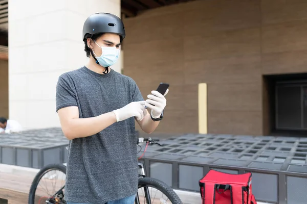 Coronavirus salgını sırasında akıllı telefondan harita kullanan genç teslimatçı.