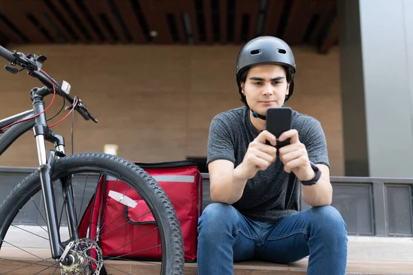 Homem Entrega Latina Usando Aplicativo Móvel Enquanto Sentado Bicicleta — Fotografia de Stock