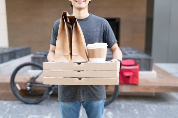 Midsection of food delivery man carrying parcel while standing on footpath