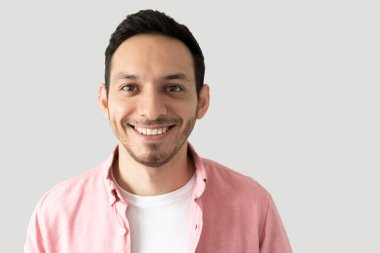 Stüdyoda gri bir arka planda mutlu görünen yakışıklı bir gencin vesikalığı.