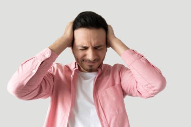 Stresli bir adam ellerini başının üstüne koyup stüdyoda şaşkın şaşkın bakıyor.