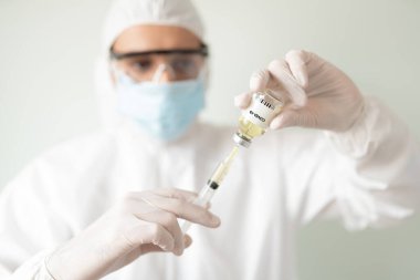 Koruyucu ekipmanlı bir doktorun portresi bir hasta için COVID19 aşısıyla bir şırınga hazırlıyor.