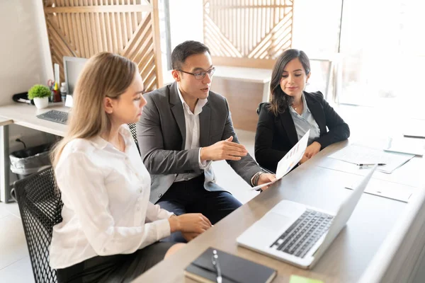 Ofiste toplanan üç iş adamından oluşan bir grup, bir belge üzerinde tartışıyor.