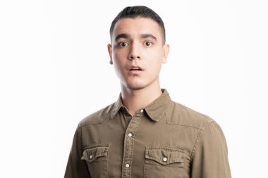 Şaşırmış ve şok olmuş Latin bir adam, bir stüdyoda beyaz bir arka plana karşı duruyor.