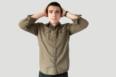 Gündelik giysiler içinde yakışıklı bir adam başının üstünde el ele tutuşuyor ve göz teması kurarken stresli görünüyor.