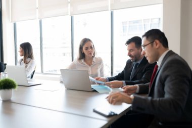 Şirket profesyonellerinden oluşan bir ekip ofis toplantı odasında belgeler üzerinde tartışıyor.