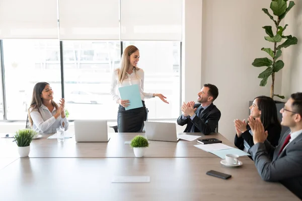 テーブルの周りに座っているビジネスマンのグループとオフィスでの会議中に女性同僚のための手を拍手 — ストック写真