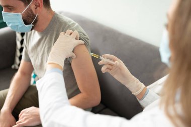 Ofisindeki kadın doktordan aşı alan İspanyol bir adamın yakın çekimi.