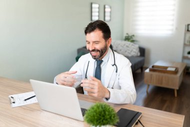 Arkadaş canlısı İspanyol doktor evden çalışıyor ve bir video görüşmesinde bir hastayla konuşuyor.