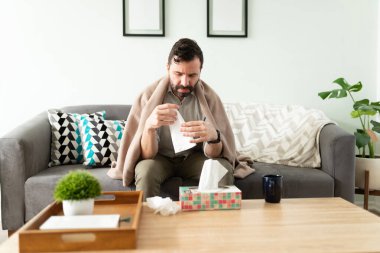 Çekici İspanyol adam evde dinlenmeye çalışırken burnu için mendil alıyor.