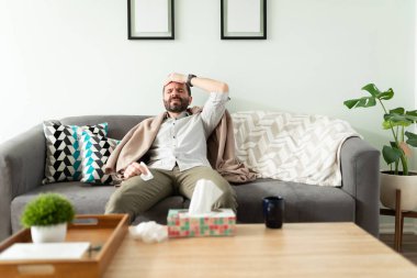 Hasta İspanyol adam alnına dokunuyor ve evde dinlenmeye çalışırken ateşi var.