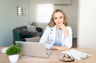 Evde çalışan ve kendinden emin görünen beyaz bir doktorun portresi.