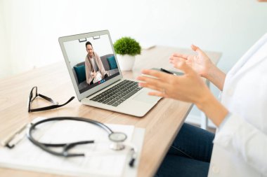 İnternetteki bir video görüşmesi sırasında bir hastaya tıbbi danışmanlık yapan bir kadın doktor.