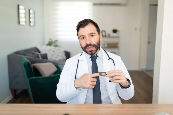 Handsome Hispanic doctor talking to an online audience and explaining the proper use of a pulse oximeter