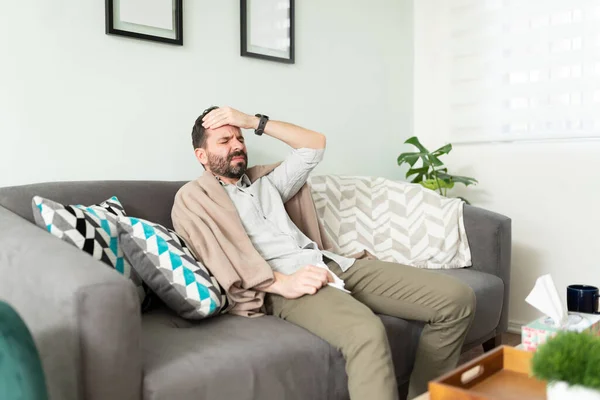 Hombre Latino Sentado Sofá Tocándose Frente Mientras Tiene Fiebre Siente —  Fotos de Stock