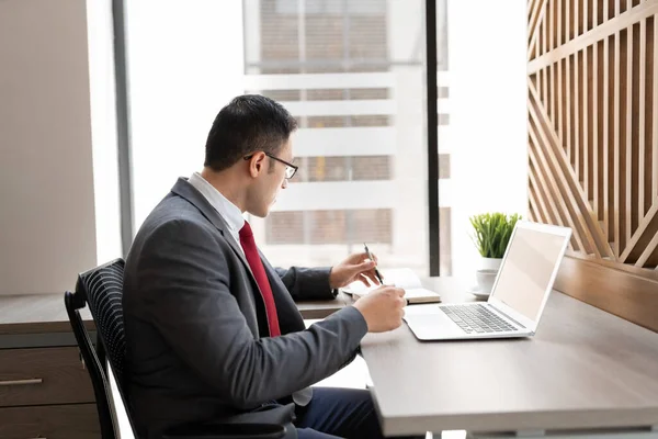 Joven Hombre Negocios Haciendo Notas Diario Mientras Trabaja Ordenador Portátil — Foto de Stock