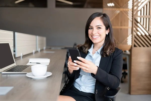 Leende Ung Affärskvinna Med Mobiltelefon Vid Skrivbordet Kontoret — Stockfoto